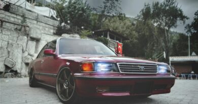 A classic luxury sedan with bright headlights parked on a paved outdoor area.