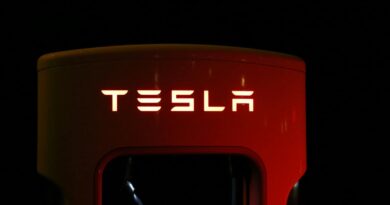 Close-up of a Tesla charging station illuminated at night, showcasing modern automotive technology.