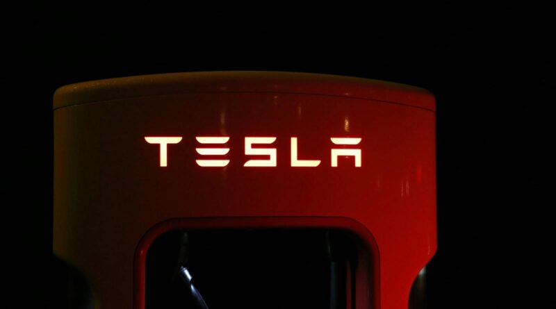 Close-up of a Tesla charging station illuminated at night, showcasing modern automotive technology.